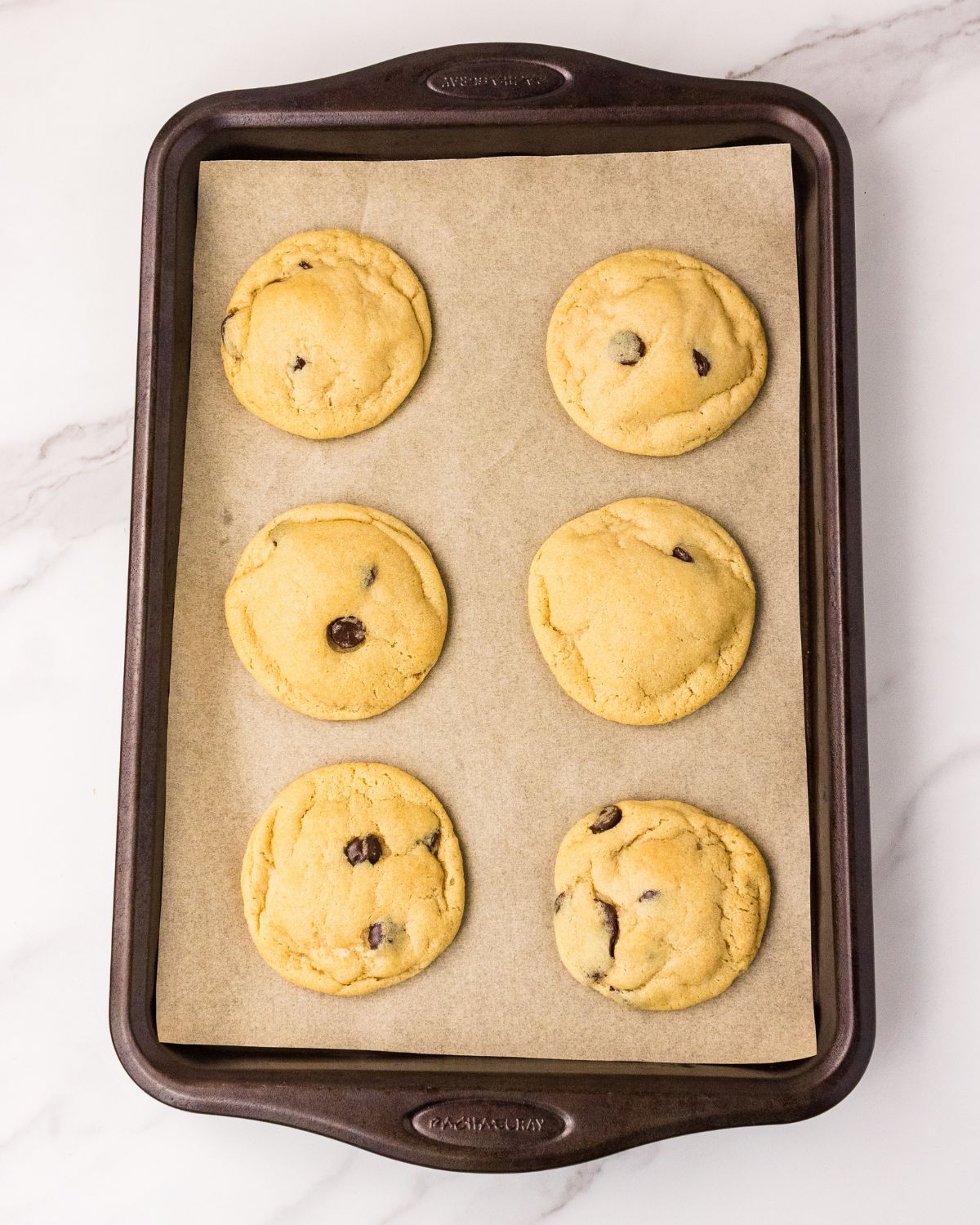 Cookie dough baked on to a baking sheet to make chocolate chip cookies no eggs.