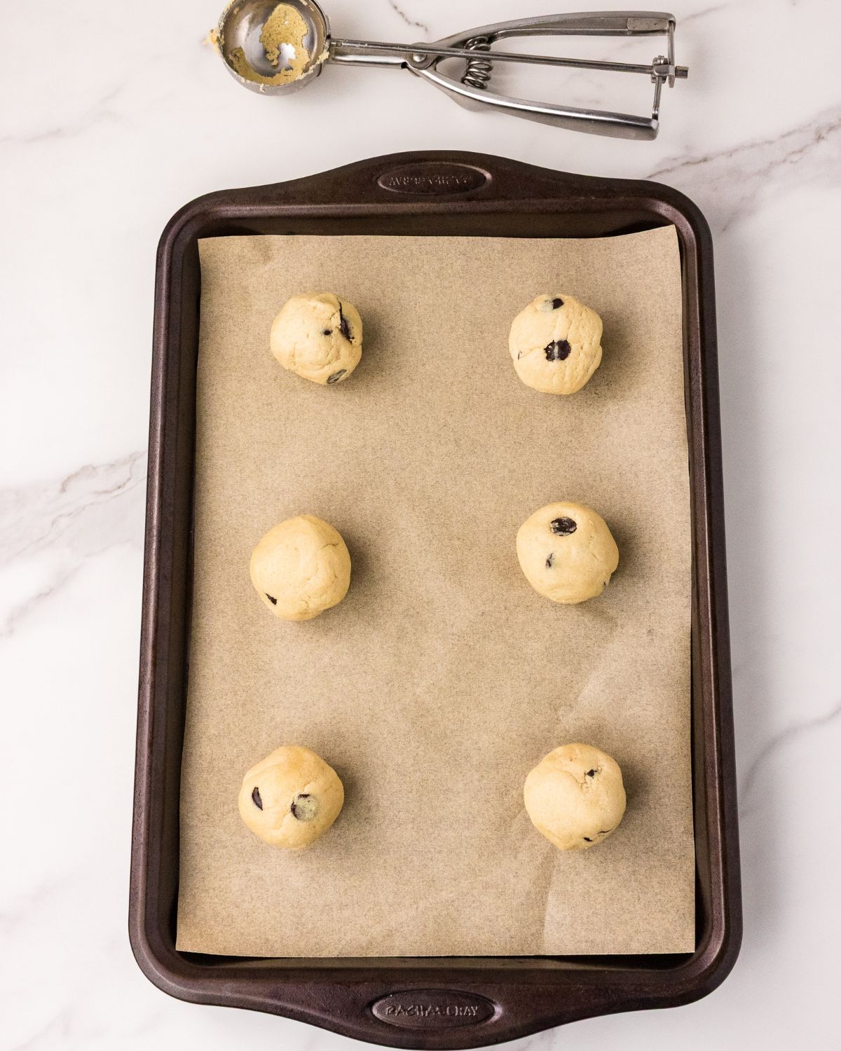 Cookie dough scooped on to a baking sheet to make eggless chocolate chip cookies