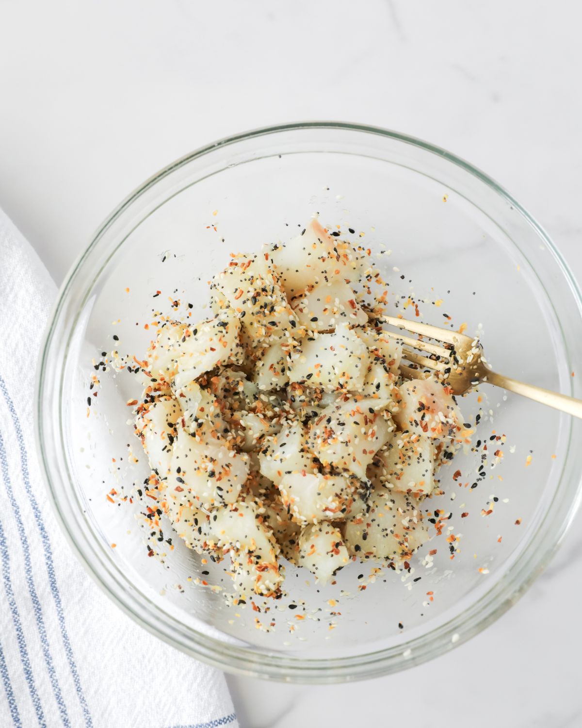 A bowl of cubed cod in olive oil and everything seasoning to make air fryer fish nuggets.