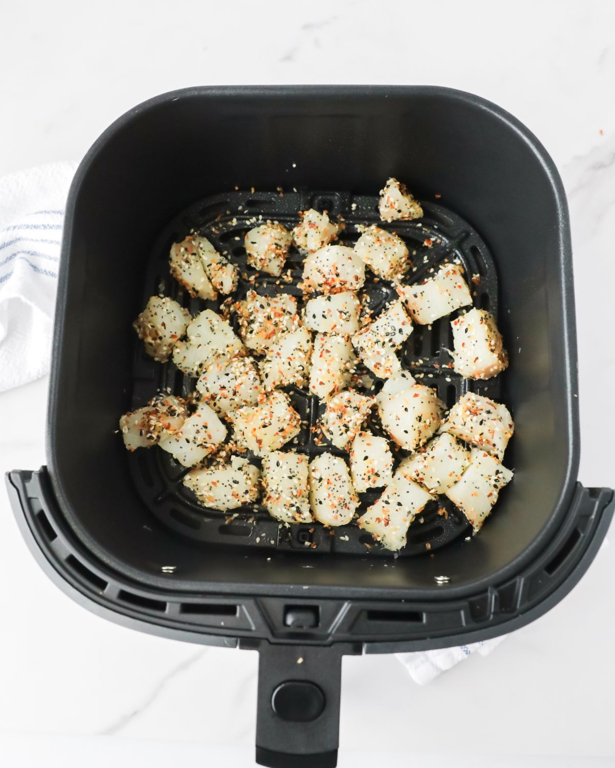 An air fryer with everything bagel seasoned fish nuggets in the air fryer.