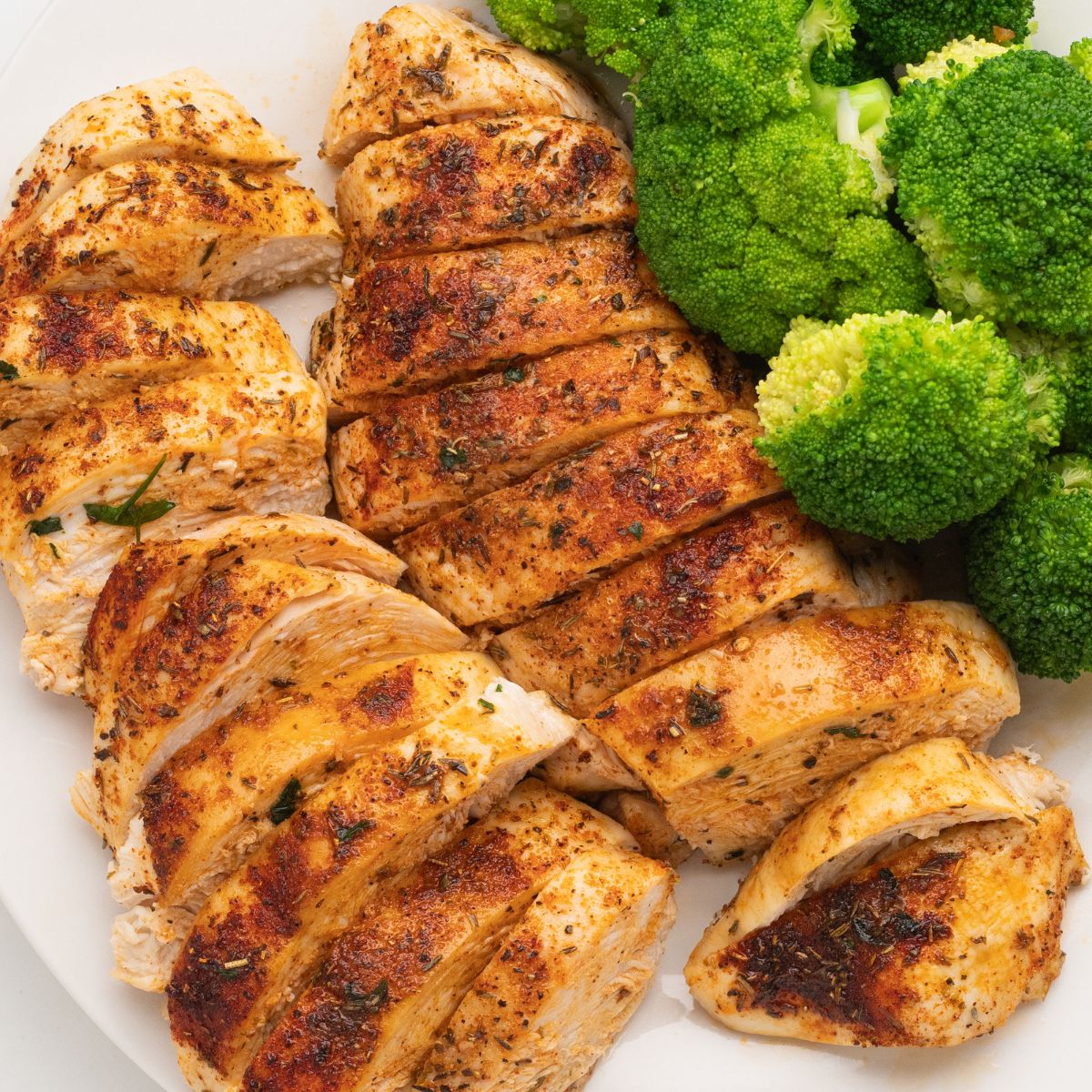 Baked Boneless Chicken Breasts with a dry rub seasoning on a white plate.