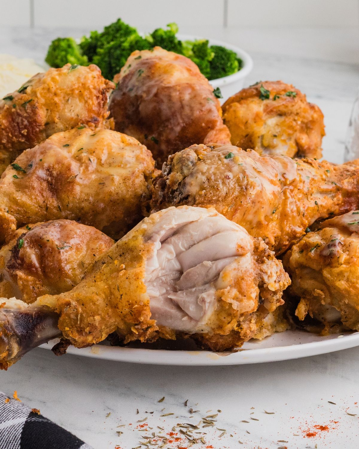 Baked Chicken Drumsticks that were oven fried on a plate with a bite out of one of the chicken legs.