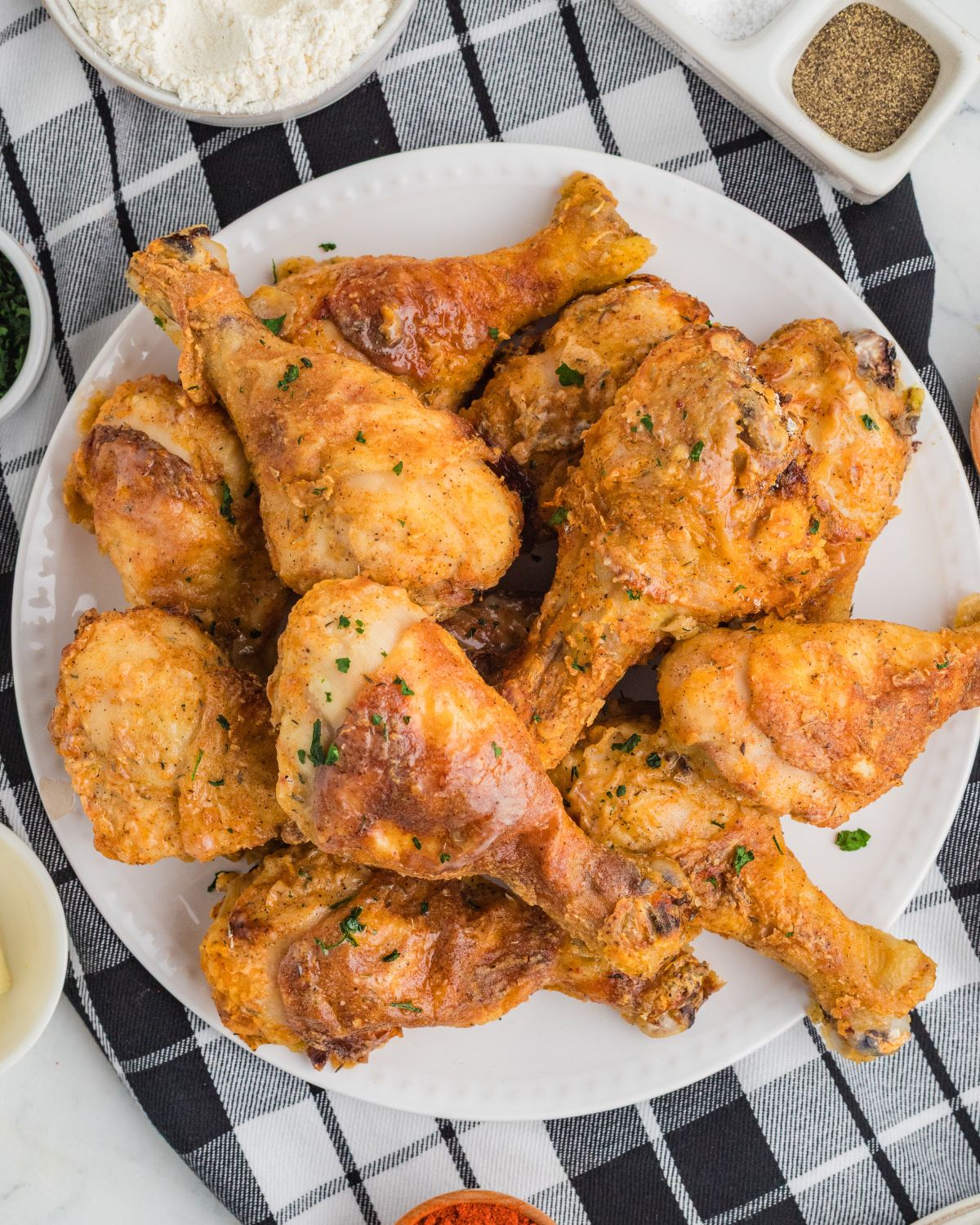 Crispy baked chicken drumsticks stacked on a plate.
