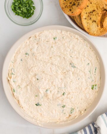 A white baking dish with crab dip in the dish ready for the oven.