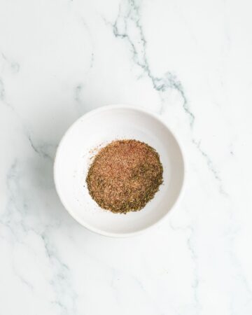 A bowl with a dry spice blend for boneless chicken breasts.