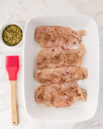 Italian seasoning on chicken breasts for pesto chicken bake.