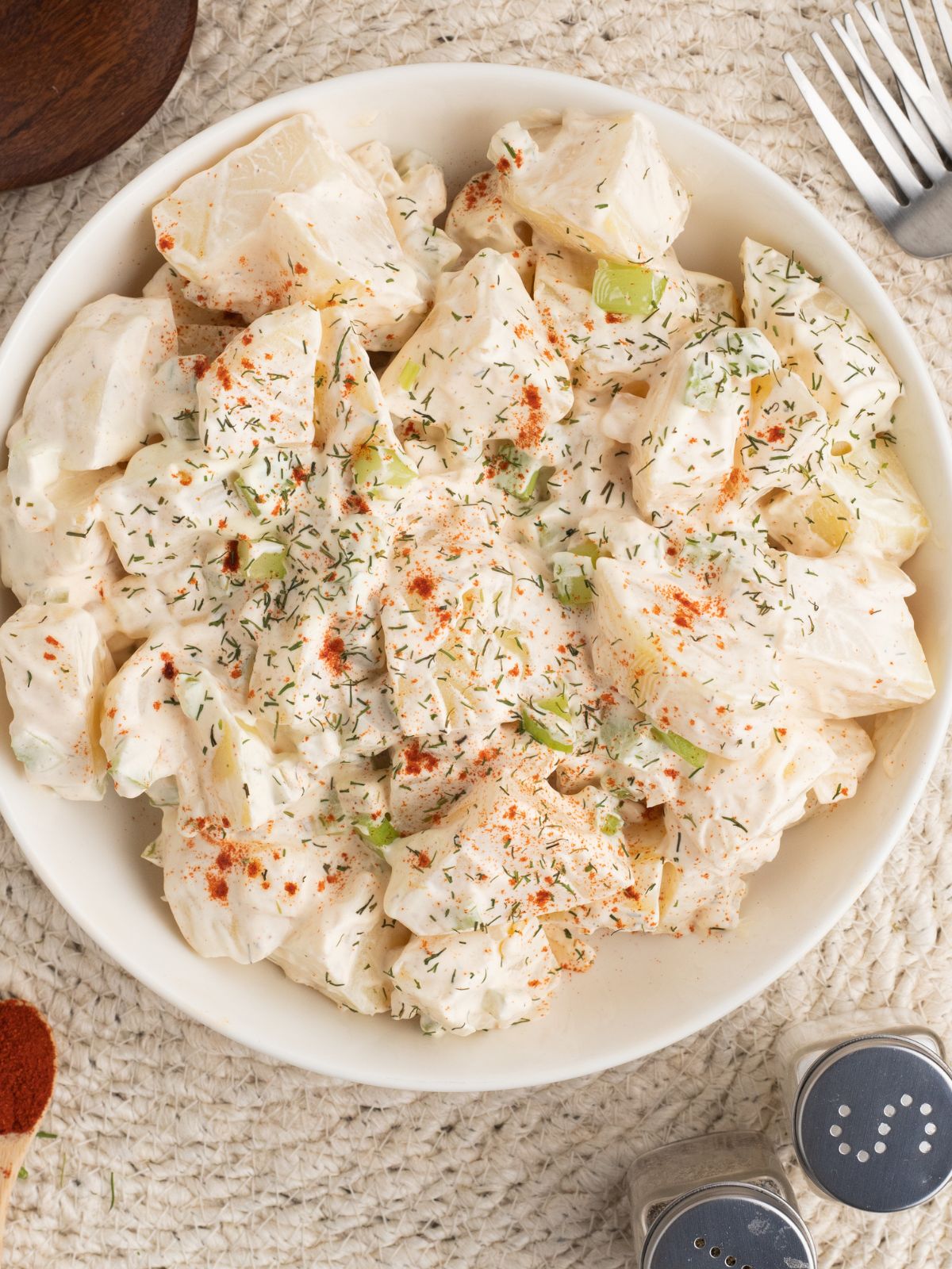 Homemade potato salad without eggs topped with smoked paprika, and dill.
