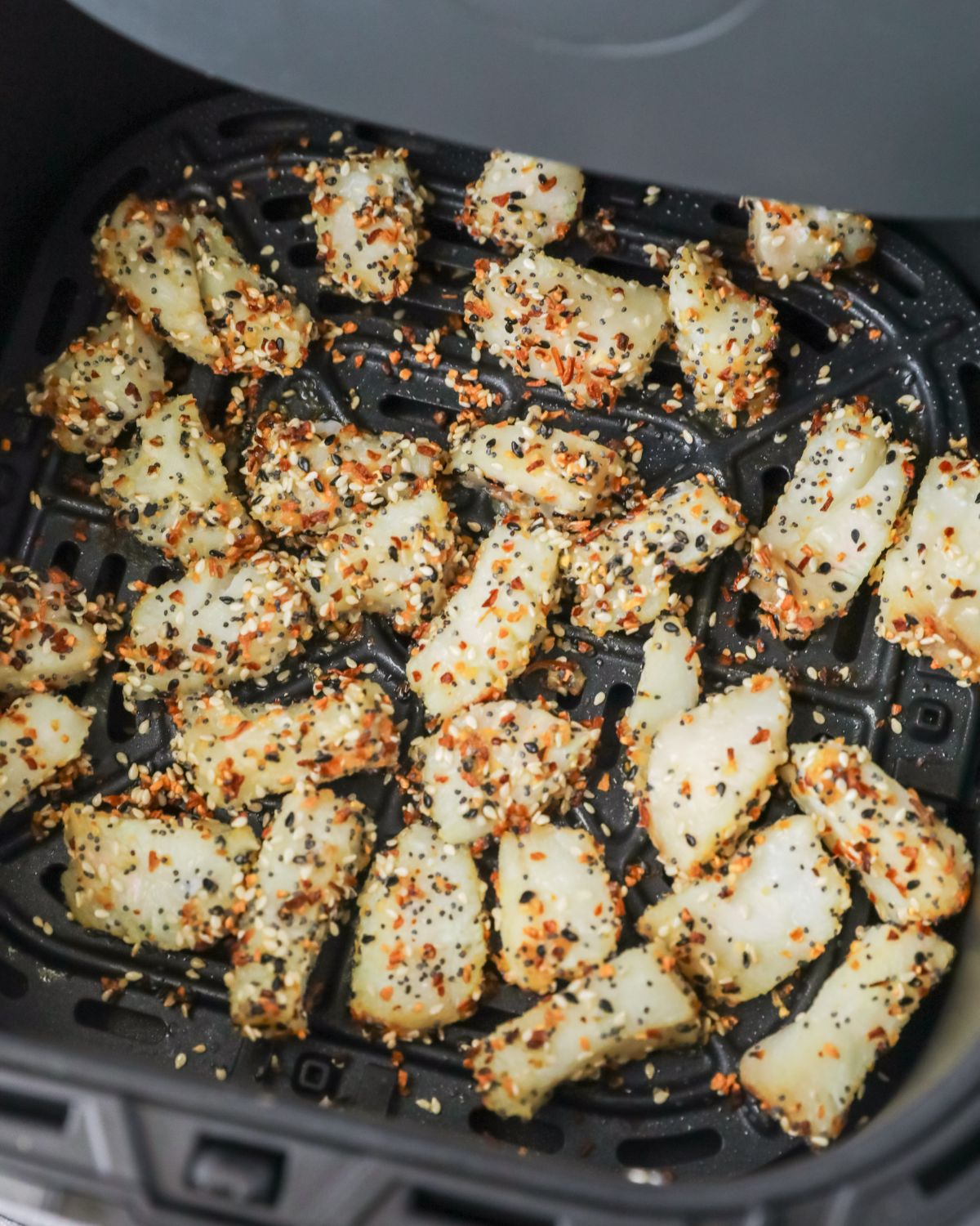 Air Fryer Fish nuggets with everything bagel seasoning in the vessel of the air fryer.