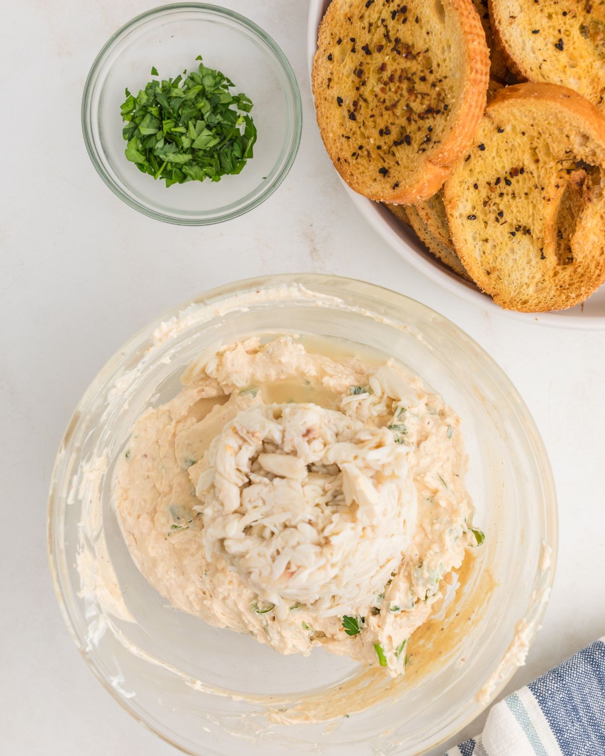 A glass mixing bowl with lump crab meat to make a crab meat dip.