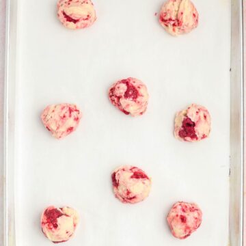 Scoops of lemon raspberry cookies on a baking sheet ready to be baked.