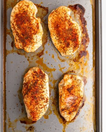 Baked chicken breasts with a dry rub on a baking sheet.