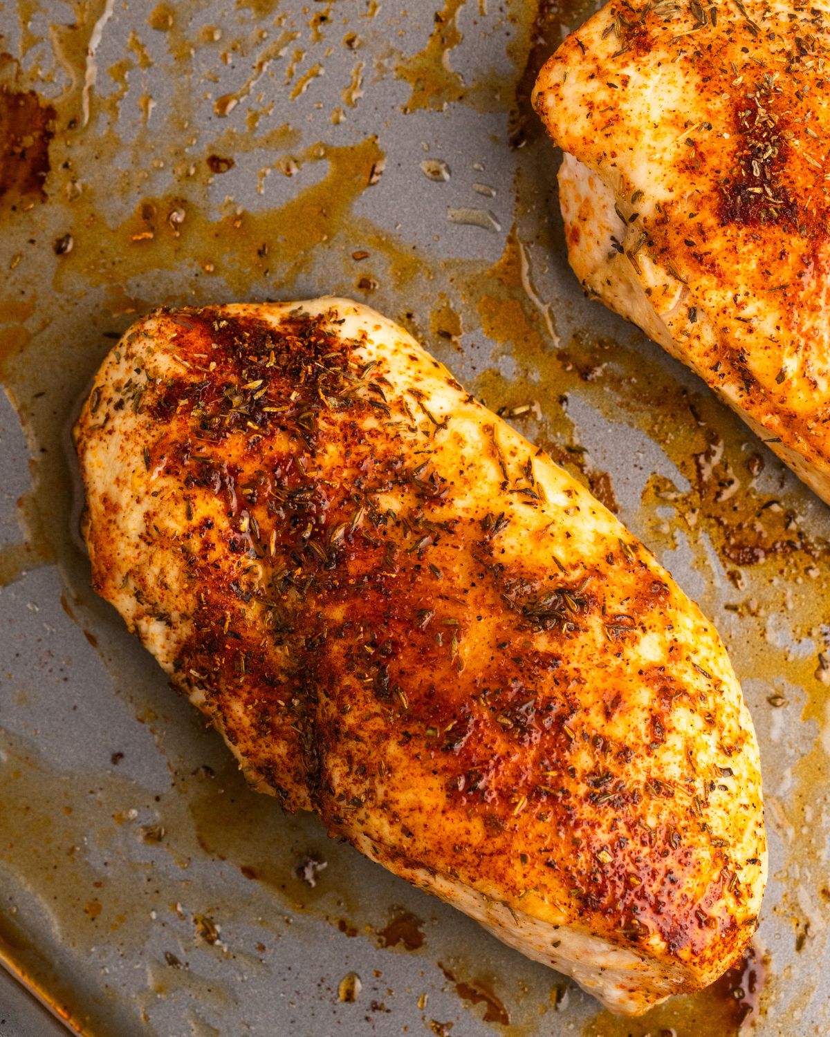 A baking sheet with oven baked chicken in a dry rub.