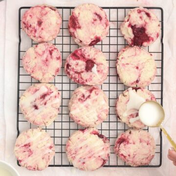 A wire rack with lemon raspberry cookies being glazed.