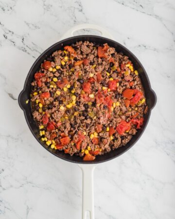 A skillet with ground beef burrito bowl ingredients to make Burrito Bowls.