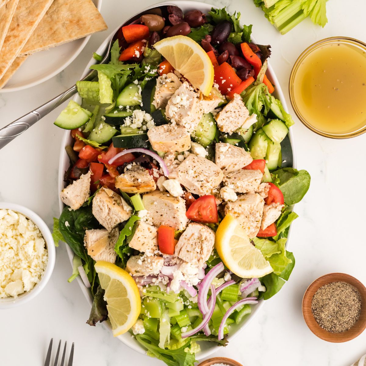 A greek salad with chicken on an oval platter.