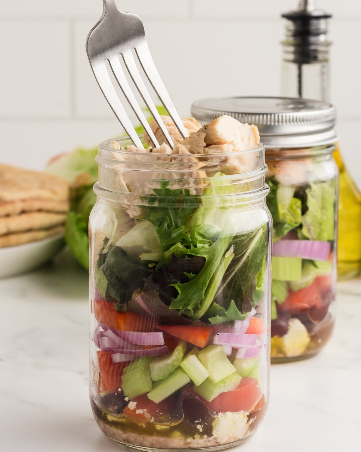 A mason jar with the ingredients to make Greek Chicken Salad. 