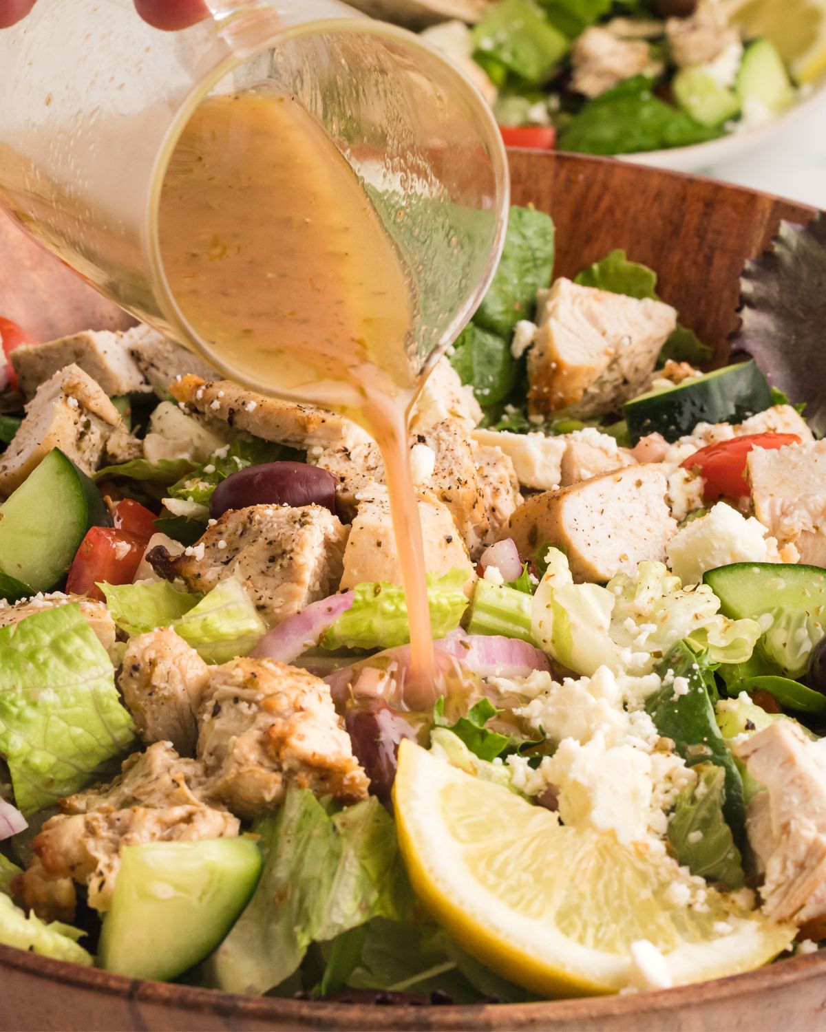 A Greek salad with a Greek marinade being drizzled on the salad.