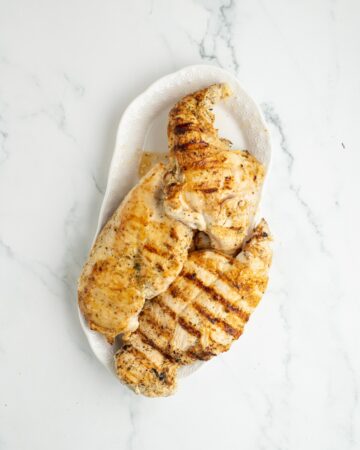 Greek yogurt marinated chicken breasts on a plate to make greek chicken gyros.