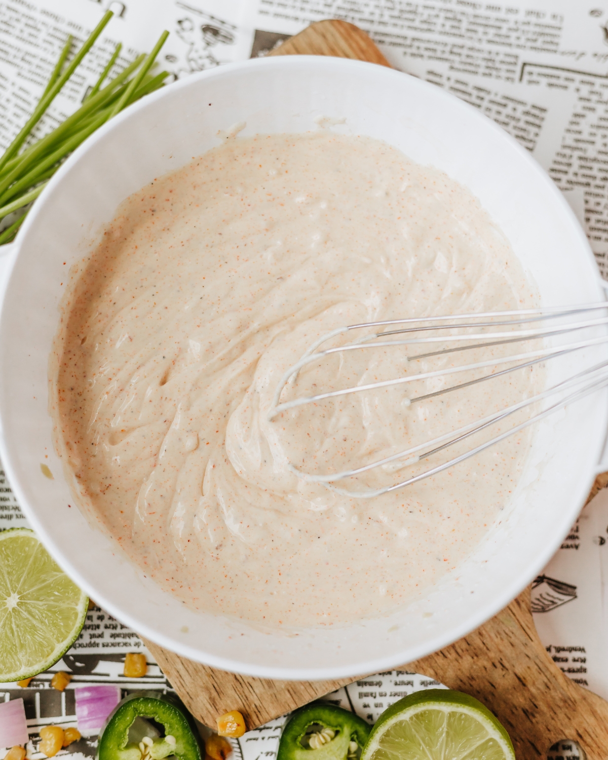 A white bowl with the whisked ingredients of spices and greek yogurt for a Mexican Corn Pasta Salad.