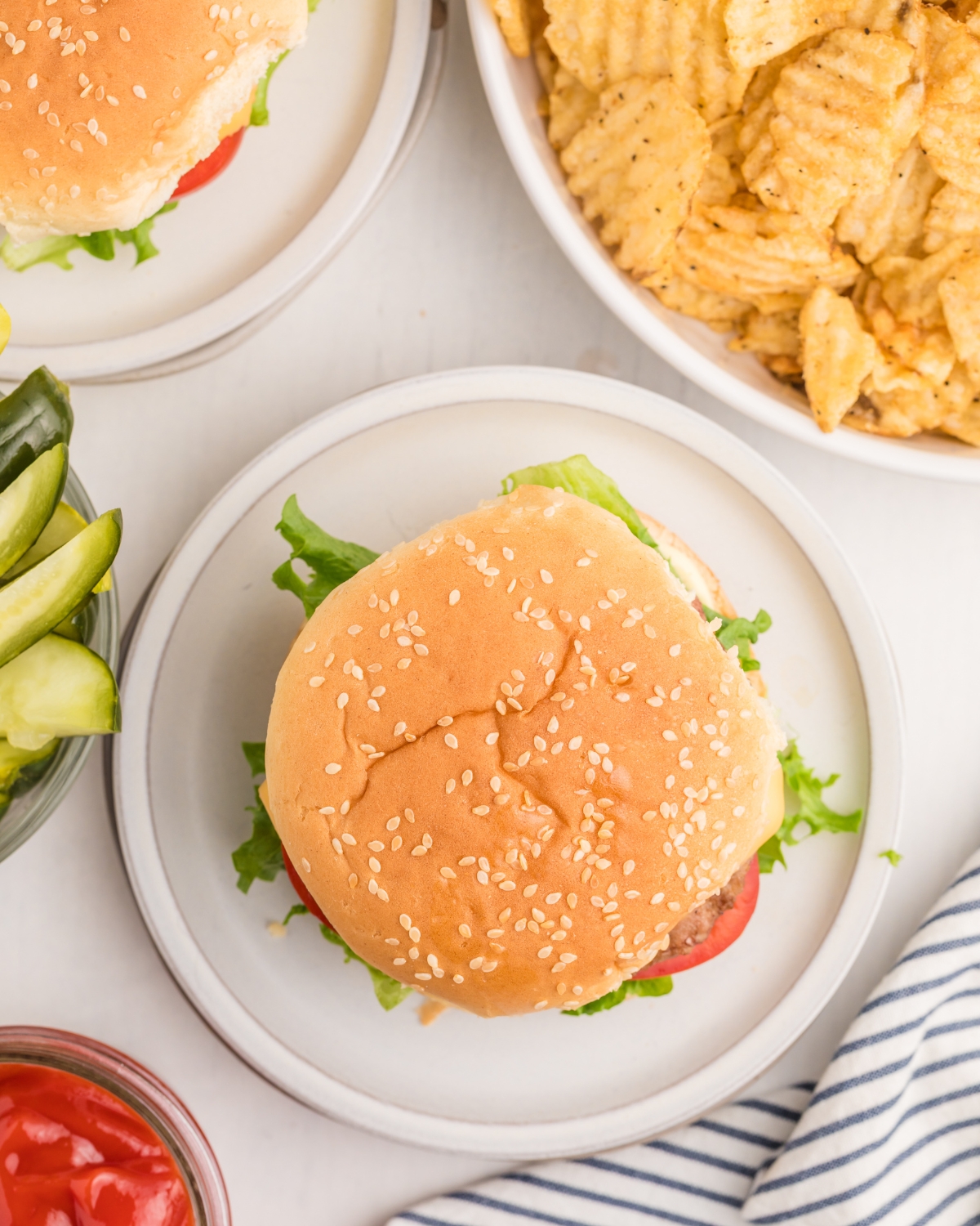 Frozen hamburgers grilled and topped with cheese, lettuce, and tomatoes, on a sesame bun.