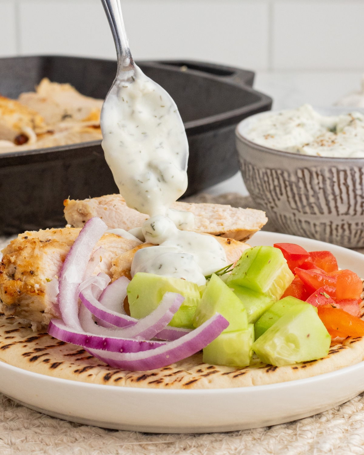 Grilled chicken on pita bread with cucumber and tomatoes with tzatziki for a grilled chicken gyro.