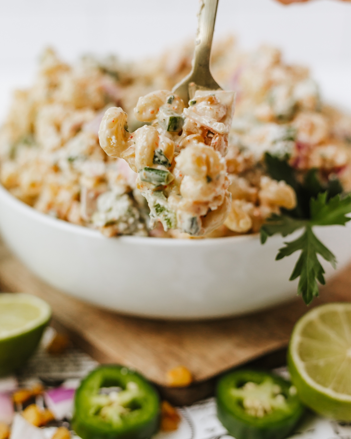 A bowl of Mexican Street Corn Pasta Salad with a fork-full of the ingredients above the bowl.