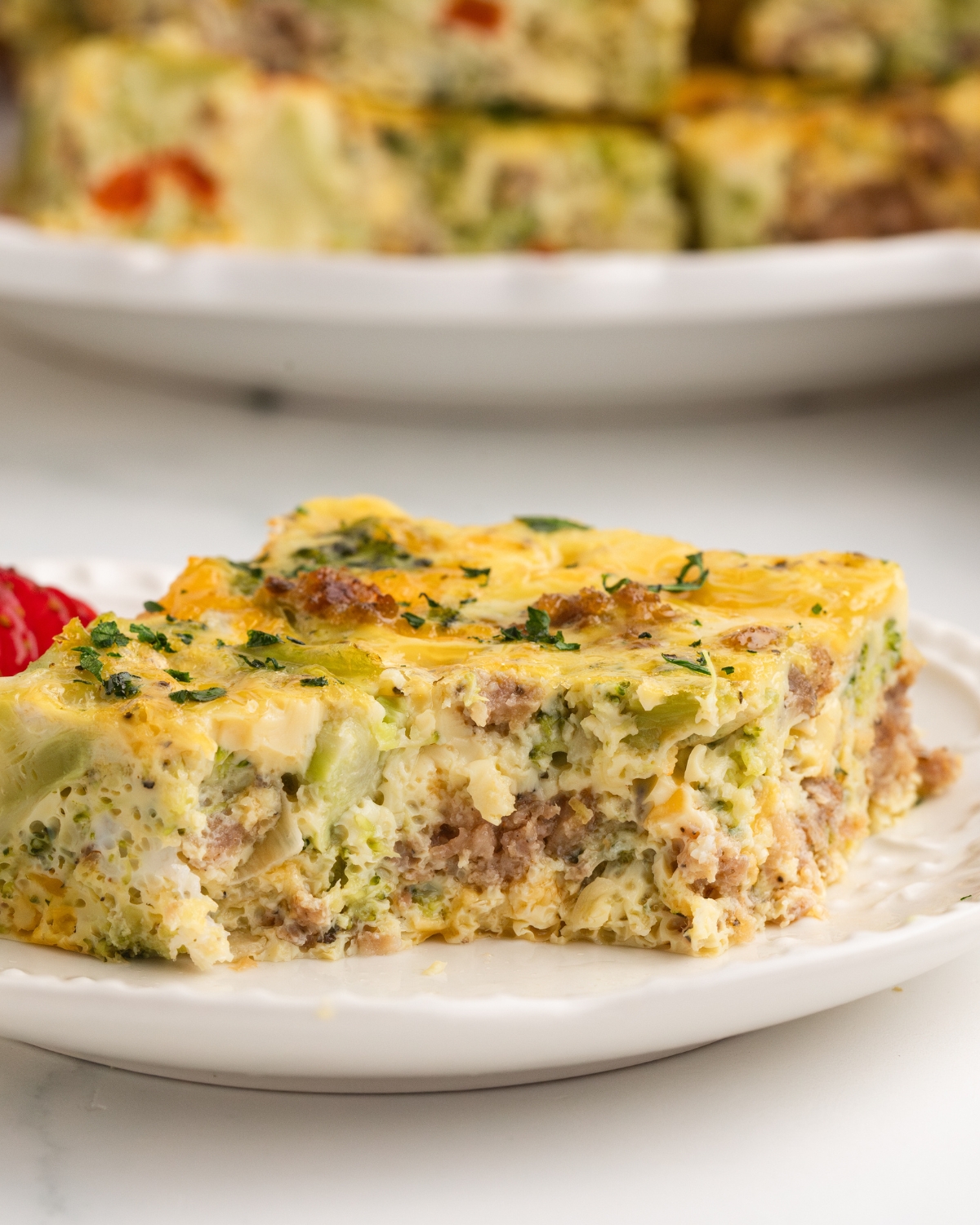 An egg broccoli sausage casserole slice on a plate.