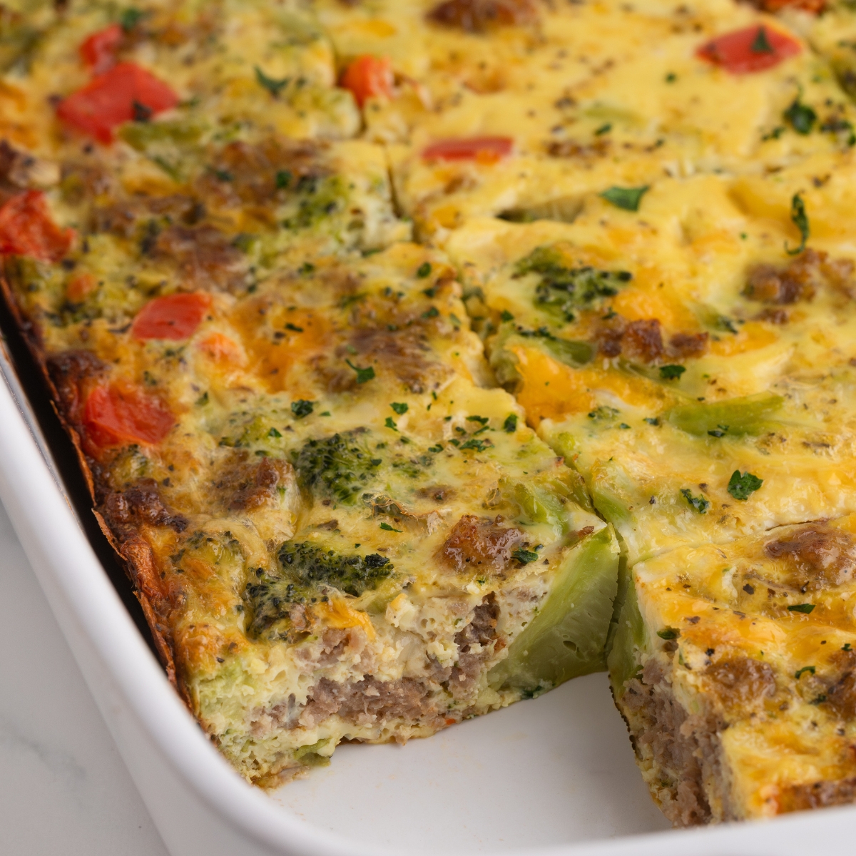 An egg casserole with broccoli, peppers, and cheese in a casserole dish.